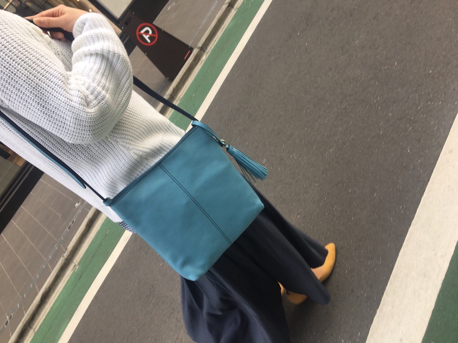 青いショルダーバッグを持って歩いている女性