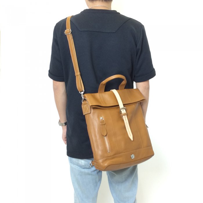 茶色いバッグを肩から掛けて立っている男性