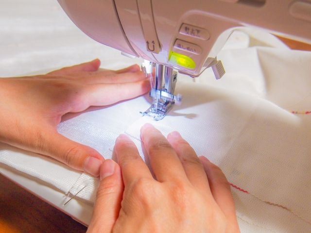 ゼッケンをミシンで縫う人の手