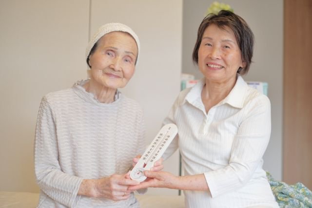 温度計を持っている高齢者と女性