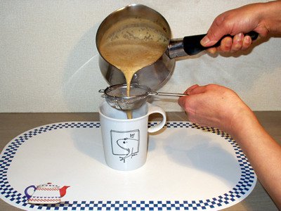 ロイヤルミルクティーを茶こしでこしながら、マグカップに注ぎます