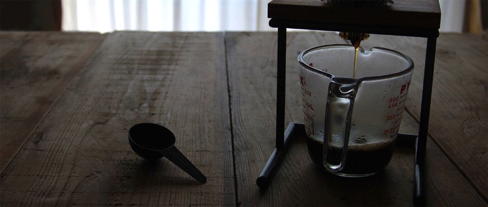 古材のテーブルの上でコーヒーをドリップ中