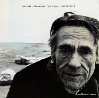 CURE, THE standing on a beach. the singles 35159-25